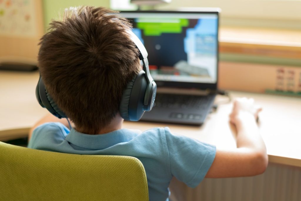 gamer boy playing on laptop at home soft focus t20 8grVAj