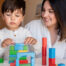 liltle preschooler kid playing with wood blocks teacher educador help homeshooling learning community montessori school